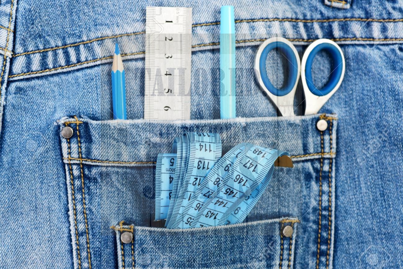 things for making clothes in back pockets of jeans close up metal scissors ruler blue pen pencil and